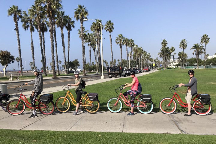 4 people sitting on electric bikes near the beach.