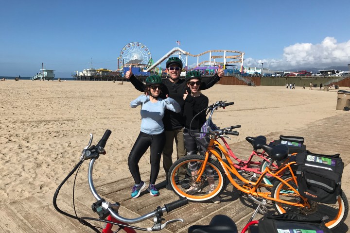 3 people posing near electric bikes.