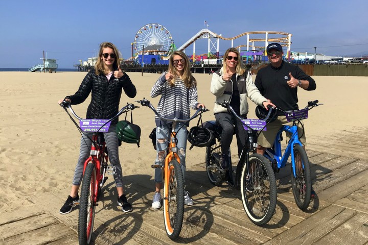 4 people sitting on electric bikes on the beach.