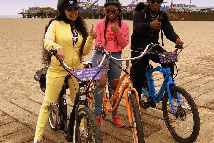 3 people sitting on bikes at the beach.